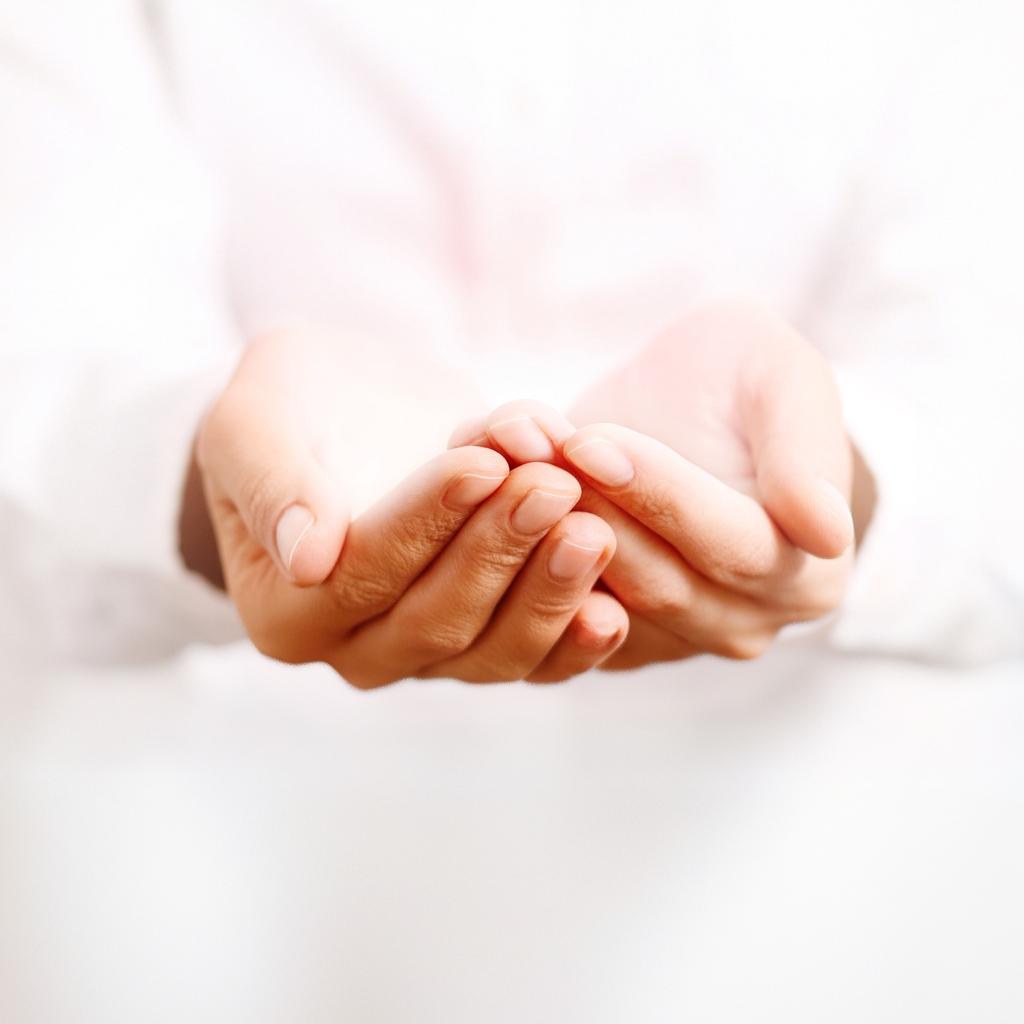 Women's hands cupped together with a soft glow representing energy healing.