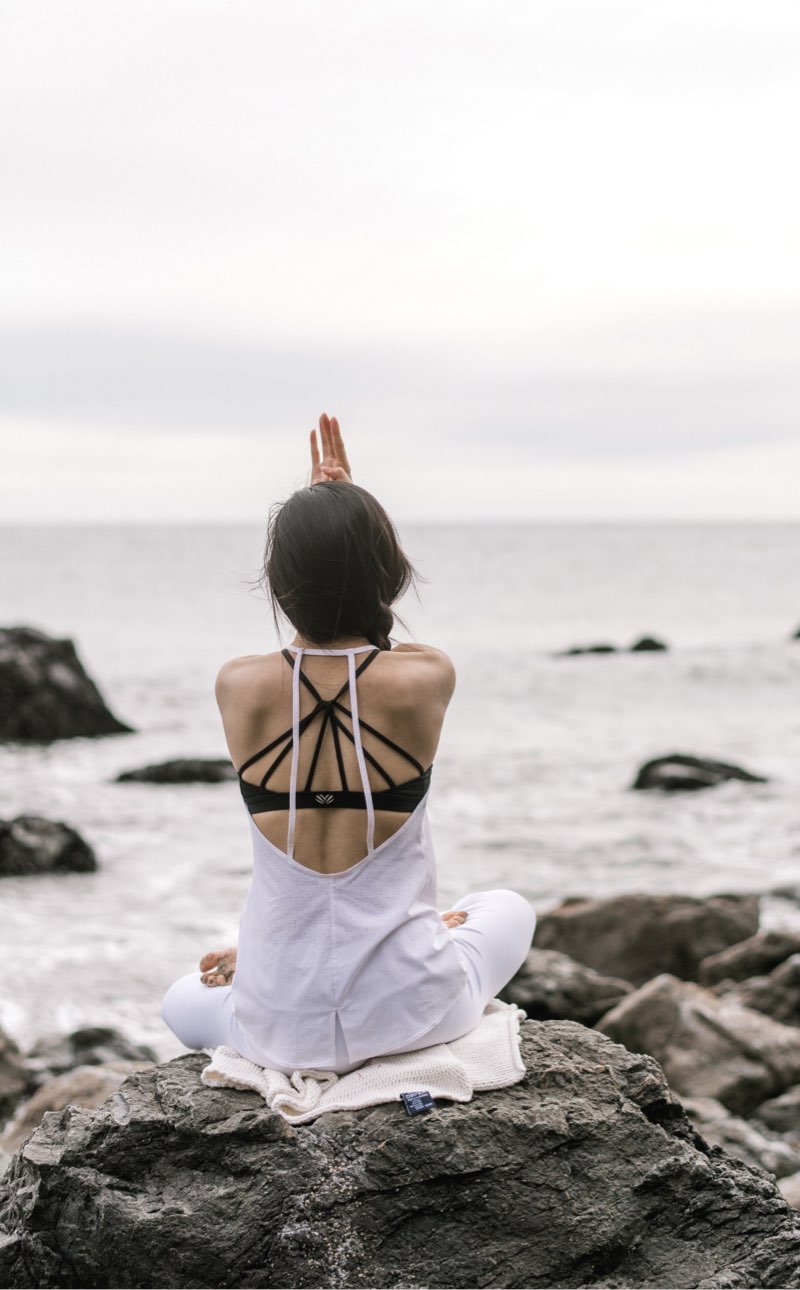 Healthy Asian woman sitting in a yoga pose by the water.